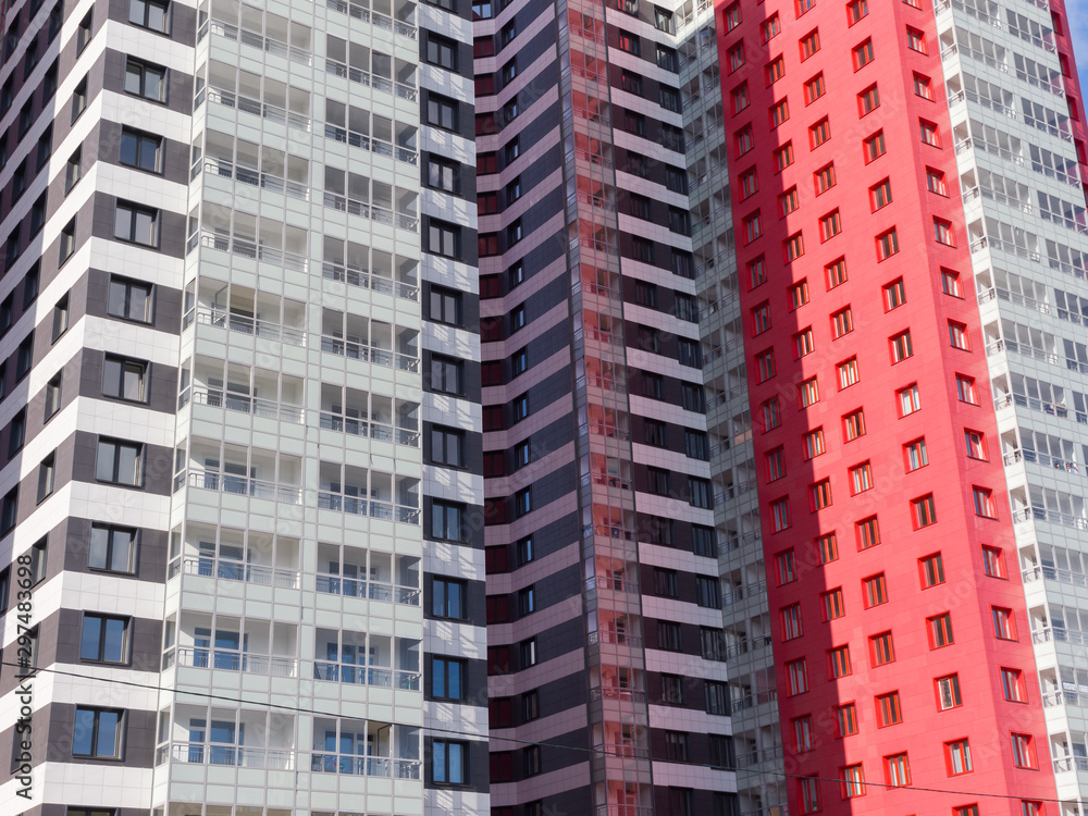 Red, black and white facades of new high-rise residential buildings. The theme of an emerging housing market under construction