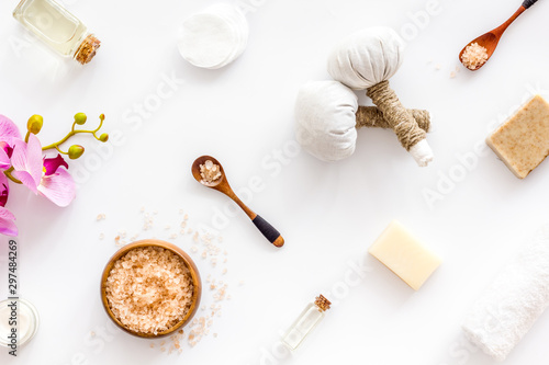 Massage table with thai herbal balls and orchids on white background top view pattern