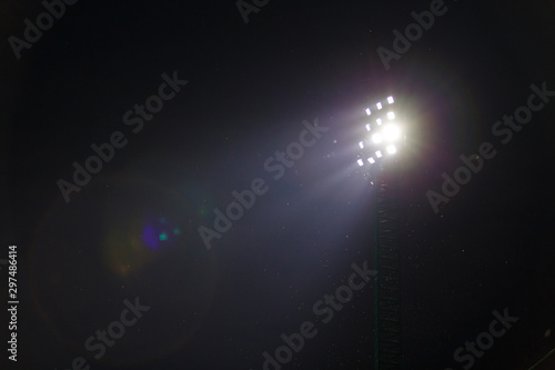 Sport light in football stadium on night time with a lot of little insects.