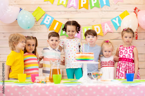 Group of adorable kids standing around festive table at birthday party