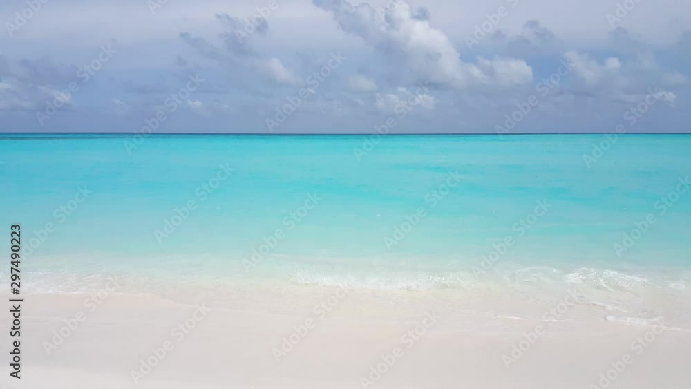 Looking out from a white sand beach over vibrant crystal clear blue waters towards some storm clouds in the Caribbean Looking out from a white sand beach over vibrant crystal clear blue waters towards some storm clouds in the Caribbean