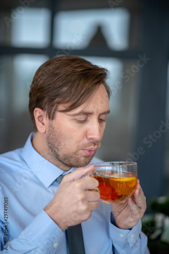 Dark-haired office worker blowing at his tea