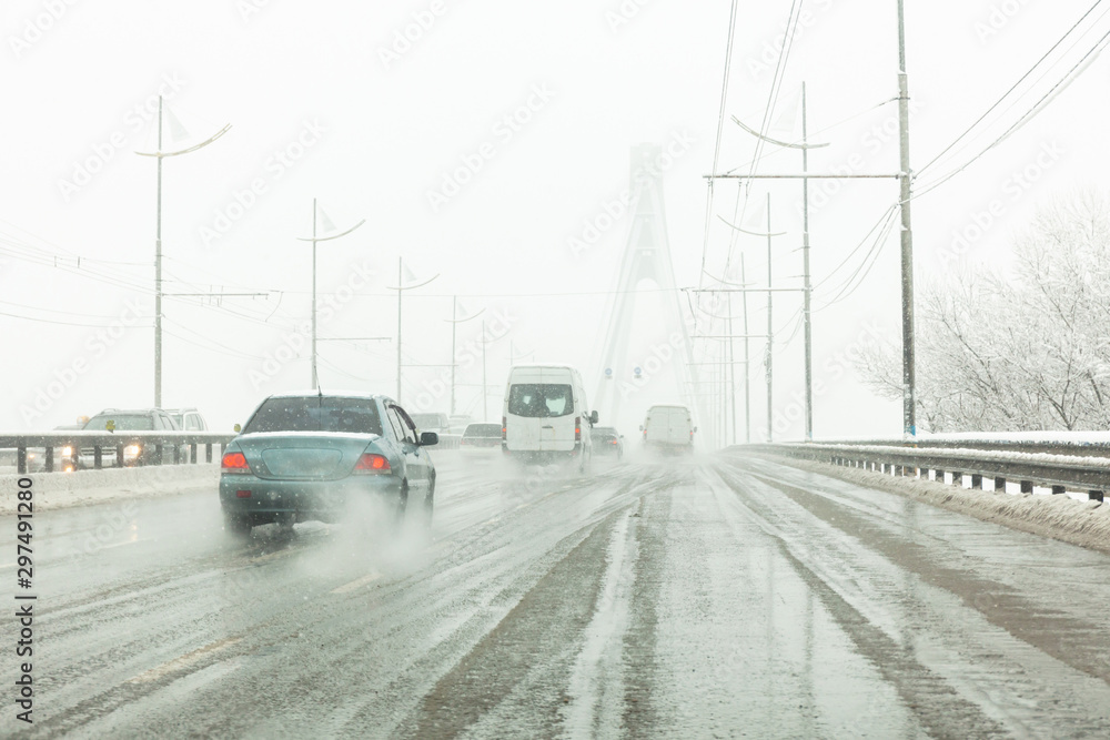 Cars drive along road with slush, snowstorm. City traffic in snow blizzard. Cars drive along road with slush, snowstorm. City traffic in snow blizzard.
