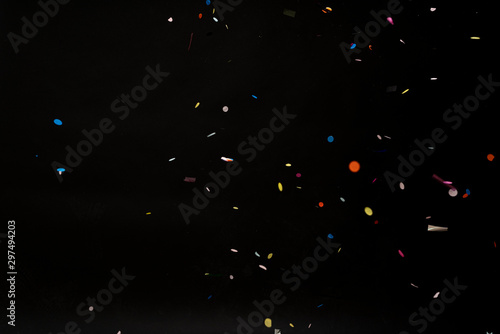 colorful party confetti flying in front of black
