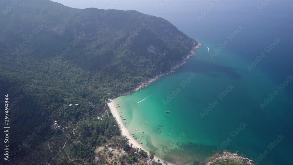 Aerial view over a sandy beach on a tropical island resort. Clear turquoise blue bay water, mountains and boats. Holiday travel destination Aerial view over a sandy beach on a tropical island resort. Clear turquoise blue bay water, mountains and boats. Holiday travel destination