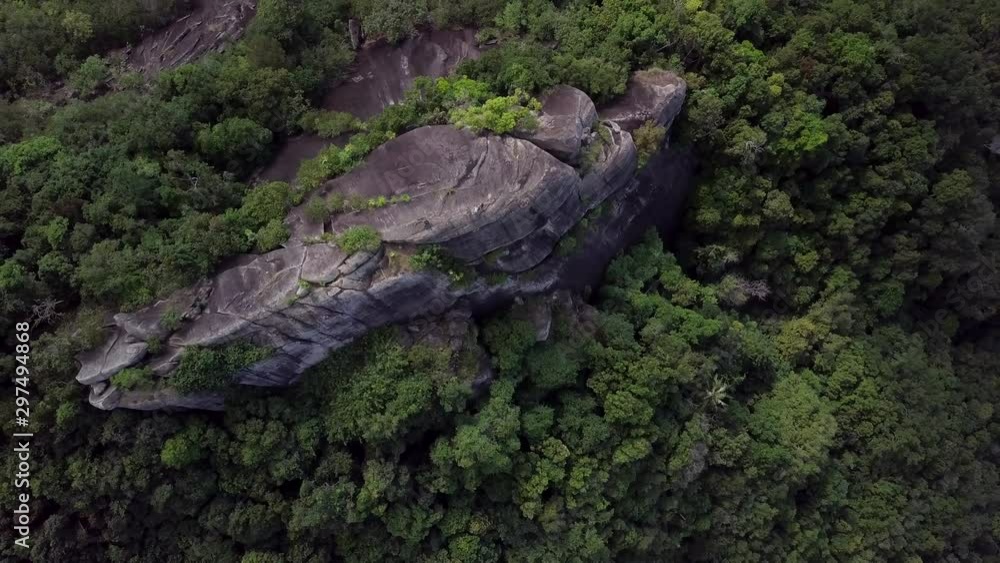 Aerial zoom out of a rocky mountain in the middle of a dense rain forest. Hikers or cliff climbers walking. 4K straight top down view. Aerial zoom out of a rocky mountain in the middle of a dense rain forest. Hikers or cliff climbers walking. 4K straight top down view.