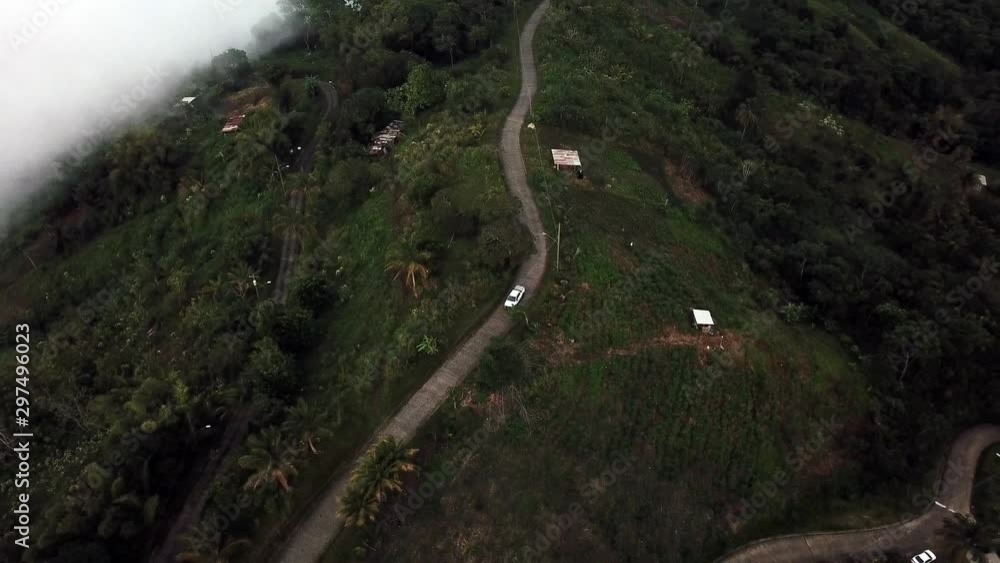 Drone shot of a car driving along a narrow road on a mountain