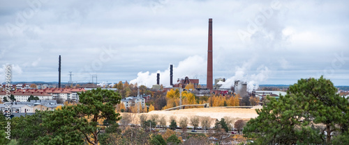 The complex of buildings of the old factory. Red brick factory chimneys with smoke. Cardboard factory in Finland, the city of Kotka