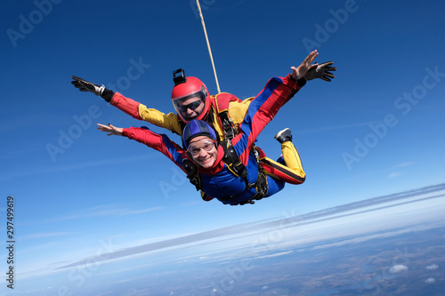 Tandem skydiving. An instructor and his woman-passenger are flying in the sky.