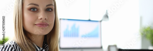 Portrait of attractive woman sitting in big important company cabinet and working at something. Gorgeous business lady looking at camera with gladness. Blurred background