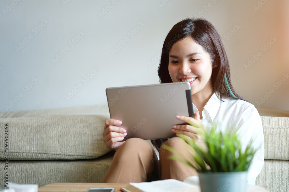 Woman relaxing on sofa in the living room enjoying sunny morning on the day Happy casual beautiful woman working on a laptop sitting in the house. Woman relaxing on sofa in the living room enjoying sunny morning on the day Happy casual beautiful woman working on a laptop sitting in the house.