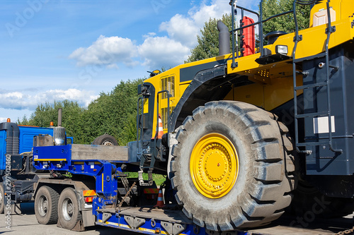 Large truck with a low platform trailer carrying a tractor. A truck for transporting heavy equipment loaded with a large tractor. Highway. Transport