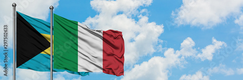 Bahamas and Italy flag waving in the wind against white cloudy blue sky together. Diplomacy concept, international relations.