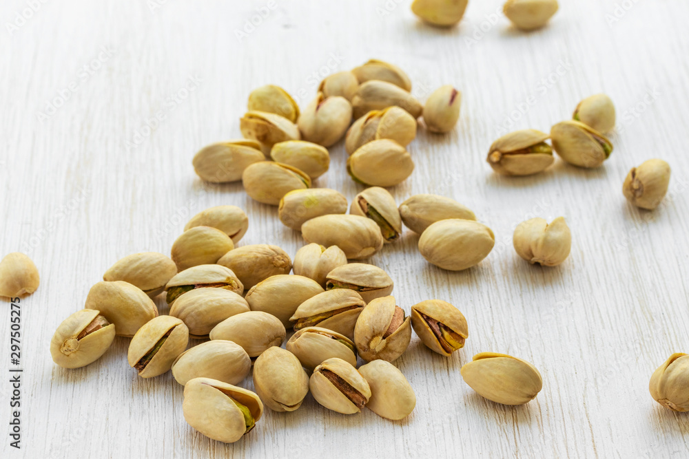 Pistachios lie in bulk on a white wooden background, top view side Pistachios lie in bulk on a white wooden background, top view side