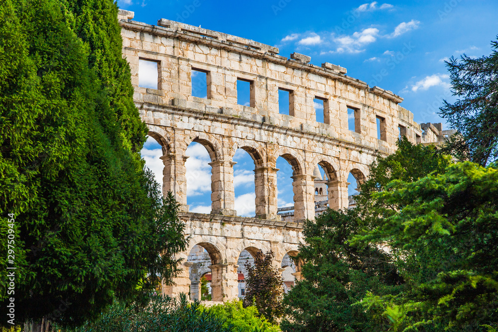 Ancient Roman Arena in Pula, Istria, Croatia, historic amphitheater landscape view through the trees in park