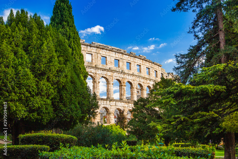 Ancient Roman Arena in Pula, Istria, Croatia, historic amphitheater landscape view through the trees in park