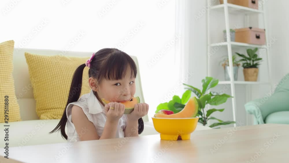 Little asian girl eating sweet melon happily. Little asian girl eating sweet melon happily.