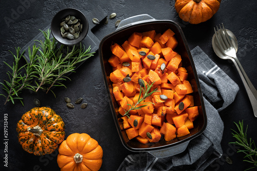 Oven baked pumpkin slices with rosemary and seeds, healthy vegetarian food, top view photo