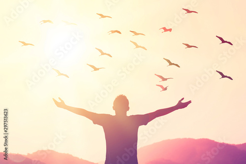 Freedom feel good and travel adventure concept. Copy space of silhouette man rising hands on sunset sky at top of mountain and bird fly abstract background.