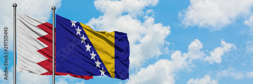 Bahrain and Bosnia Herzegovina flag waving in the wind against white cloudy blue sky together. Diplomacy concept, international relations.