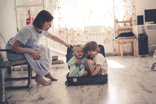 funny children hide in suitcase near mom