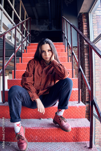 Photos young girl is sitting on the red stairs. cocky teen millennial