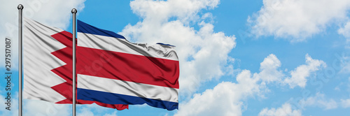 Bahrain and Costa Rica flag waving in the wind against white cloudy blue sky together. Diplomacy concept, international relations.