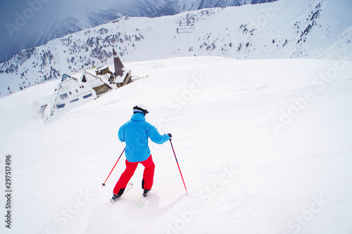 Photo from back sports man skiing on snowy slope.