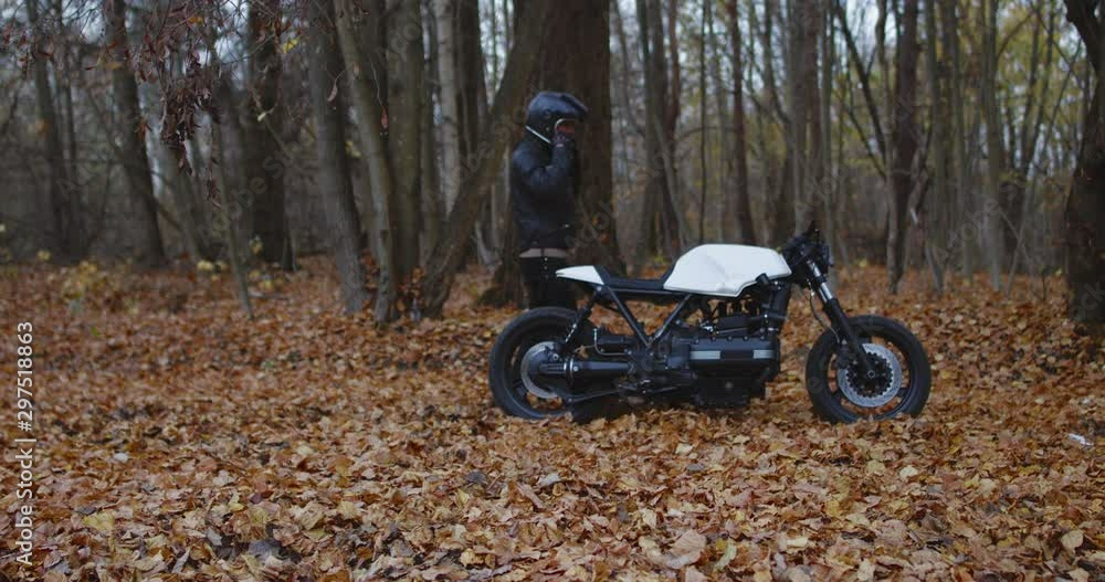 Caucasian male biker wearing leather jacket riding his custom built vintage cafe racer motorcycle on a road covered with fallen leafs in autumn. 4K UHD Caucasian male biker wearing leather jacket riding his custom built vintage cafe racer motorcycle on a road covered with fallen leafs in autumn. 4K UHD