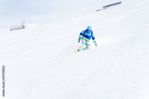 Male snowboarder rolling on hillside in afternoon.