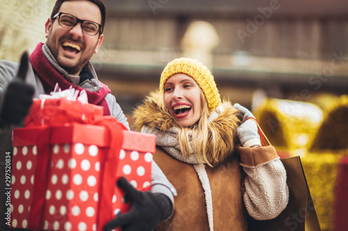 Young couple dressed in winter clothing holding gift boxes outdoor.