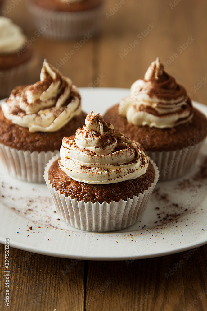 Chocolate cupcakes with whipped cream on rustic wooden table. Homemade dessert. Chocolate cupcakes with whipped cream on rustic wooden table. Homemade dessert.