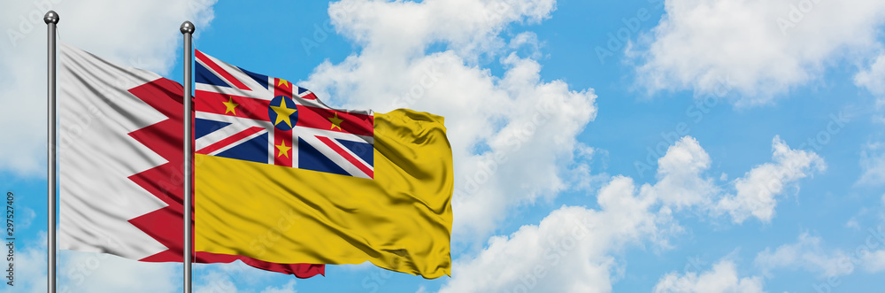 Bahrain and Niue flag waving in the wind against white cloudy blue sky together. Diplomacy concept, international relations. Bahrain and Niue flag waving in the wind against white cloudy blue sky together. Diplomacy concept, international relations.