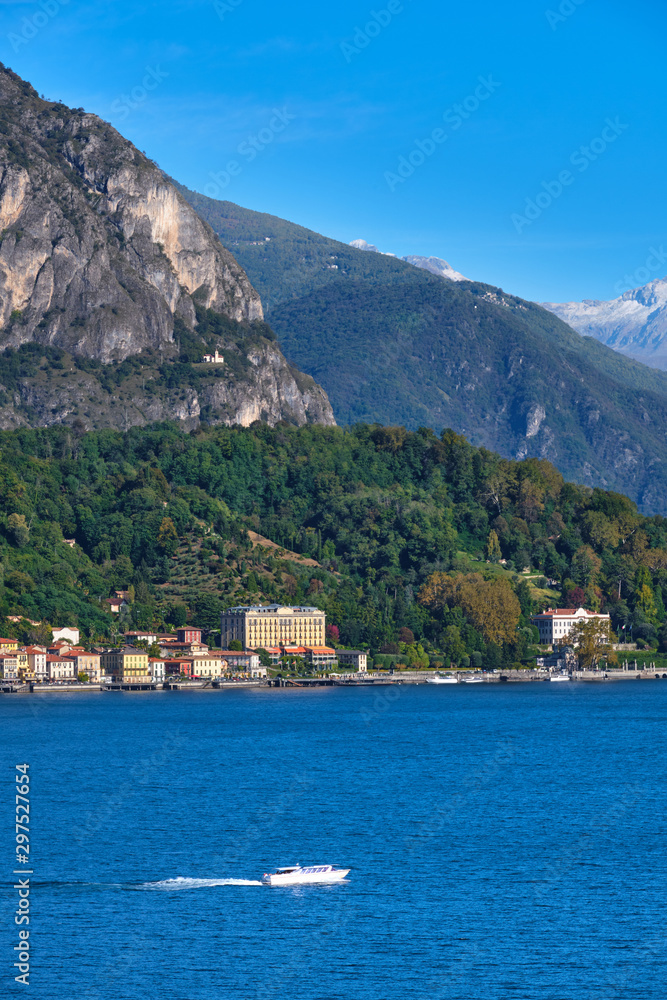 Panoramic view of Lake Como. Lombardy, Italy. Boat in motion on the water. Autumn season. Perfect clear blue sky. Panoramic view of Lake Como. Lombardy, Italy. Boat in motion on the water. Autumn season. Perfect clear blue sky.