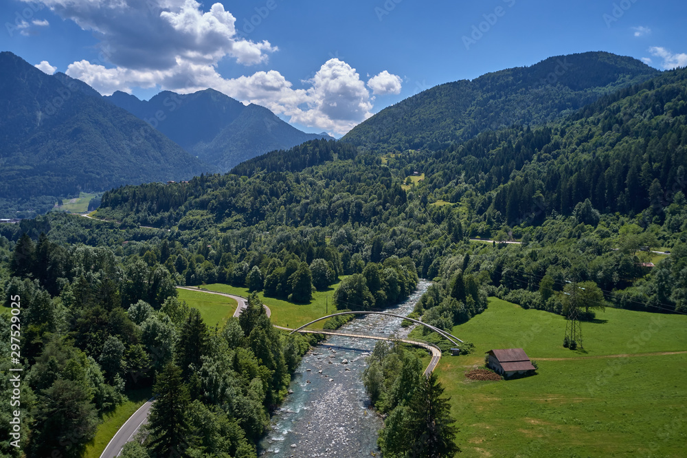 Aerial view of the Alps surrounded by meadows, forests and mountains. Flying on drone.