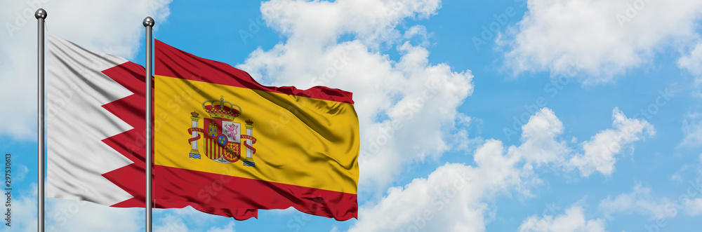 Fototapeta premium Bahrain and Spain flag waving in the wind against white cloudy blue sky together. Diplomacy concept, international relations.