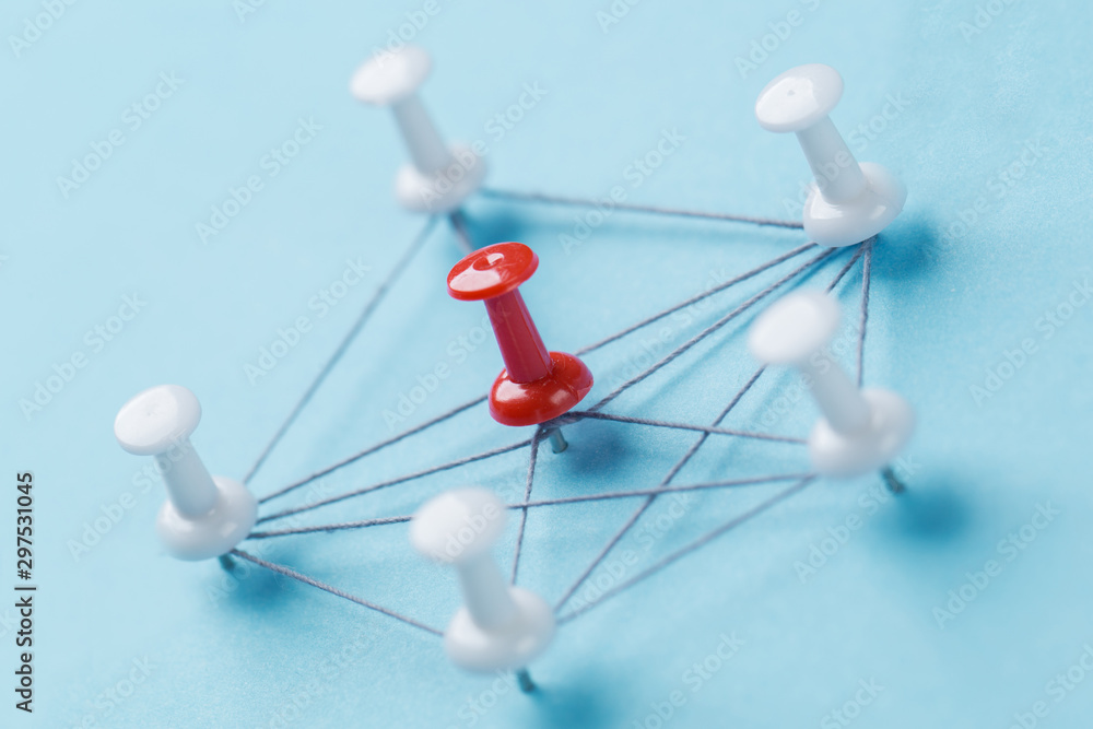 Obraz premium network with red and white pins and string, An arrangement of colorful pins linked together with string on a blue background suggesting a network of connections.