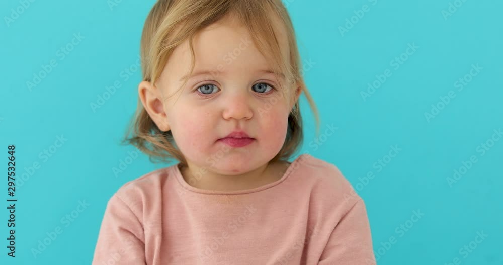 Sweet baby girl closeup portrait of child isolated on blue background, cute toddler with blue eyes Sweet baby girl closeup portrait of child isolated on blue background, cute toddler with blue eyes