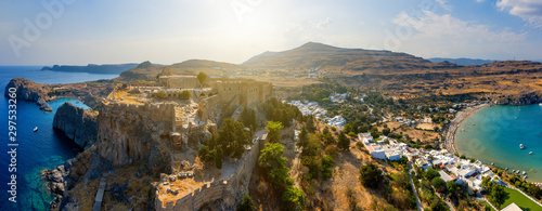 Breathtaking panoramic aerial view of Lindos town from the Acropolis of Lindos in Rhodes, Greece. Amazing colorful sunset scenery in Rhodes. Idyllic background above Aegean sea. Dodecanese, Greece.