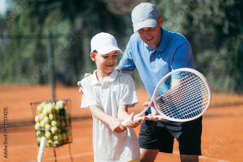 Tennis Lesson. Smiling Coach Explaining Tennis Technique to a Boy photo