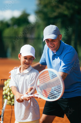 Tennis Lesson. Smiling Coach Explaining Tennis Technique to a Boy © Microgen