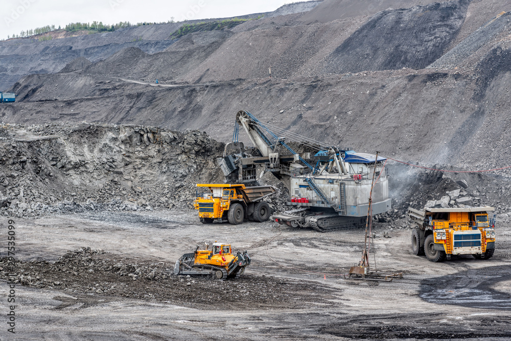 A powerful excavator loads mining trucks. A powerful excavator loads mining trucks.