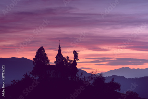 A beautiful shot of s silhouette of a church in the mountains and the pink sunset sky in the background. Great for desktop wallpaper and backgrounds © MKozloff
