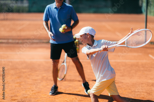 Tennis Instructor with Young Boy on a Clay Court © Microgen