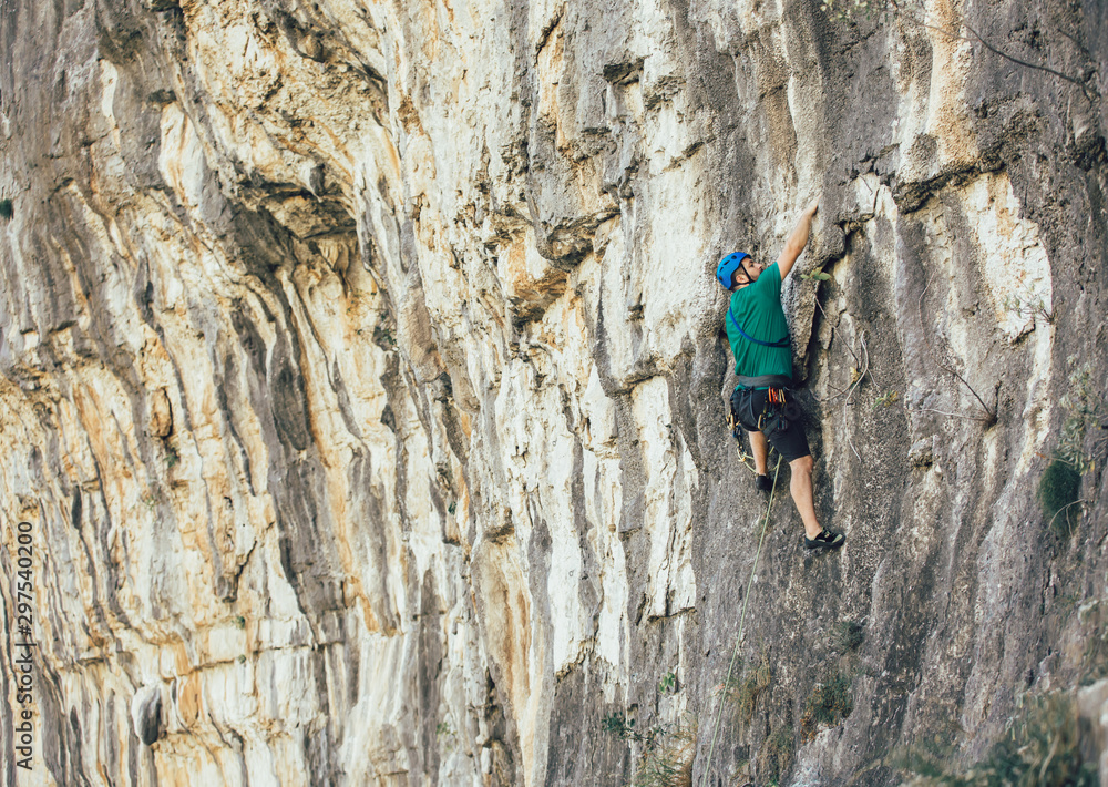 Fototapeta premium Man with a rope engaged in the sports of rock climbing on the rock.