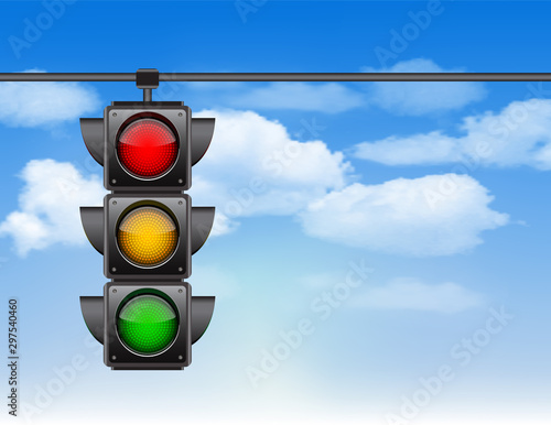 Traffic lights with all three colors on hanging against blue sky