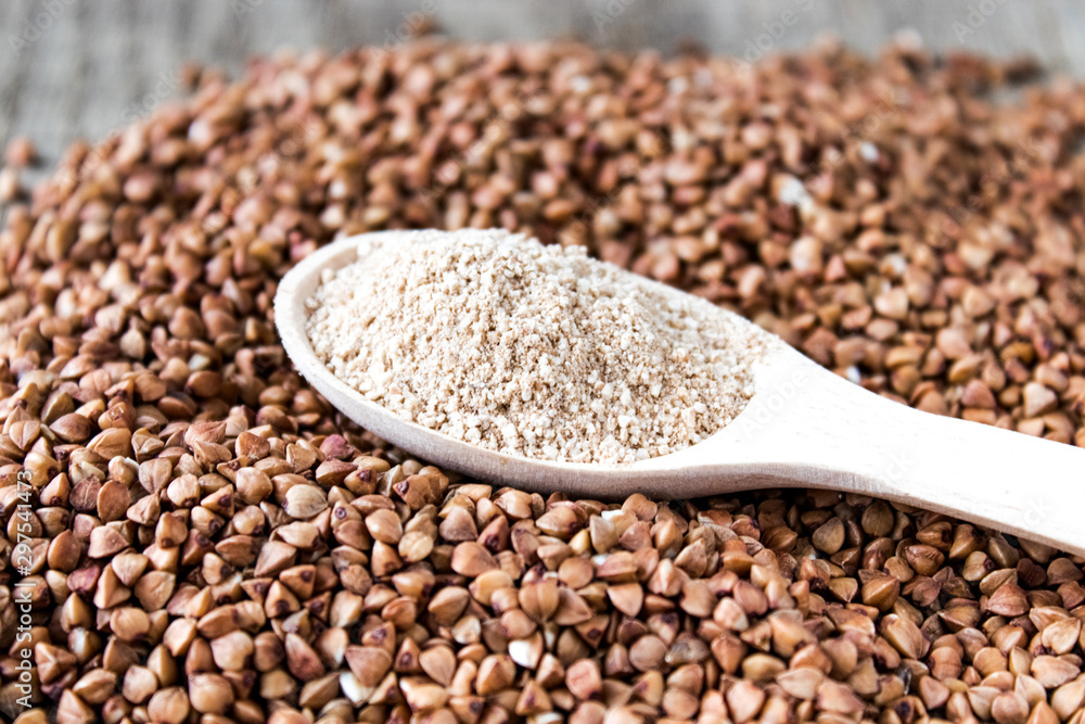 Buckwheat flour in a wooden spoon on a pile of roasted buckwheat. A pile of buckwheat flour. Buckwheat flour in a wooden spoon on a pile of roasted buckwheat. A pile of buckwheat flour.