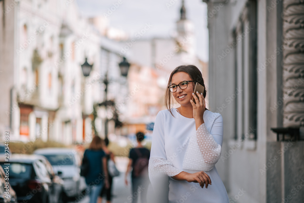 Smiling young woman talking on mobile phone in urban background.
