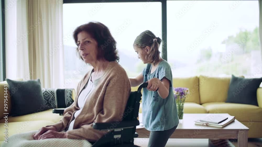Small girl and her senior grandmother in wheelchair indoors at home. Small girl and her senior grandmother in wheelchair indoors at home.