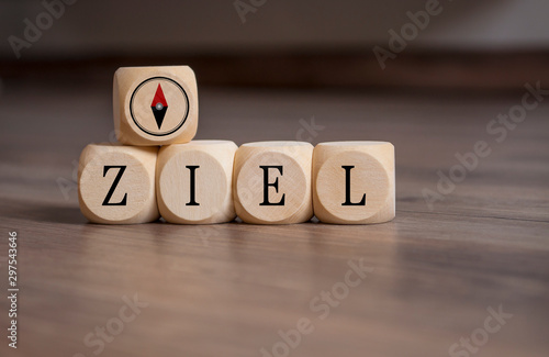 Cubes and dice with the german word for goal or target - Ziel with icon compass on wooden background